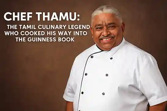 Chef Damu smiling in his chef coat while preparing a large traditional meal